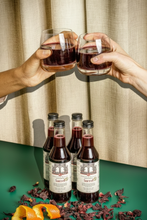 Load image into Gallery viewer, A beautifully arranged gift set of 4 bottles of Brooklyn Brewed Sorrel mocktail, each decorated with a thin red ribbon in a festive wedding party setting. This healthy, nut-free spiced hibiscus roselle beverage is crafted in an allergen-free facility. An ideal alcohol-free gift from a Black-owned, Woman-owned, and Caribbean-owned business, perfect for weddings, Dry January, Passover, Father's Day, or Mother's Day.
